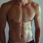 Close-up of athletic shirtless man showcasing muscular and fit physique.