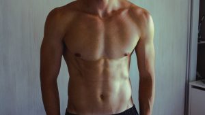 Close-up of athletic shirtless man showcasing muscular and fit physique.